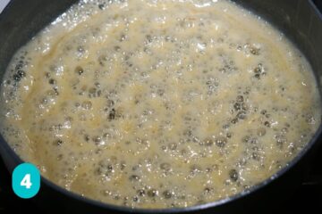 Sugar and milk simmering in a pan on stovetop.