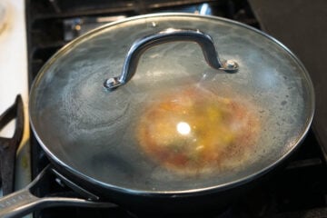 Bhakri pizza covered on stovetop to cook.