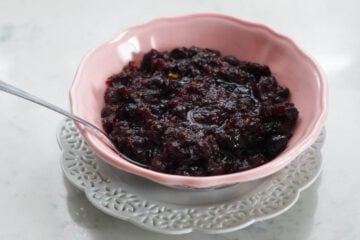 Dried cranberry sauce in a pink bowl with a spoon.