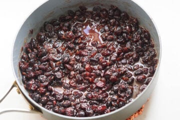 Dried cranberries in a sauce in a pan.