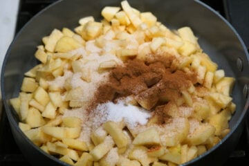 Salt and cinnamon added to apples in a pan.