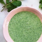 Yogurt chutney in a pink bowl with mint to the side.