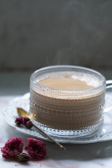 Rose chai in a mug with rose petals to the side.