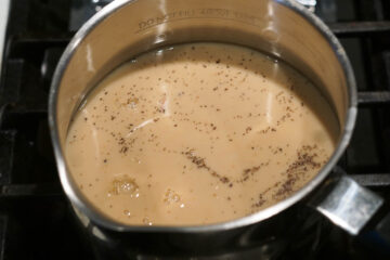 Milk added to rose chai in a pot.