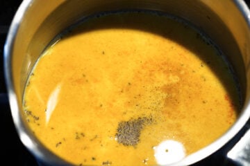 Black pepper and turmeric powder in milk in a pot.