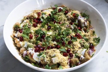 Sev, pomegranate, and chopped coriander on top of the aloo chana chaat.