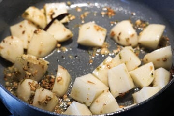 Potatoes, garlic, and spices in a non-stick pan.