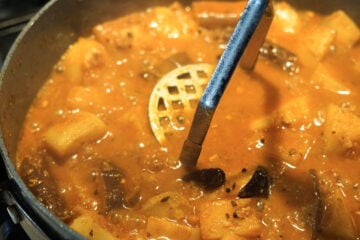 Mashing eggplants with potato masher.