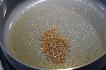 Cumin seeds in ghee in a pot.