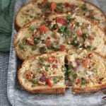 Chili cheese toast with veggies and spiced cheese on top.