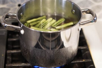 Pot on stove-top with moringa and potatoes in it.