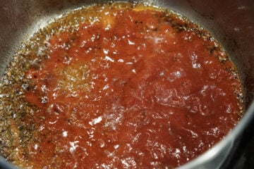 Crushed tomatoes added to tadka.