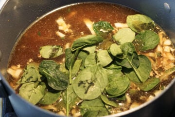 Vegetable stock and spinach added to pot.