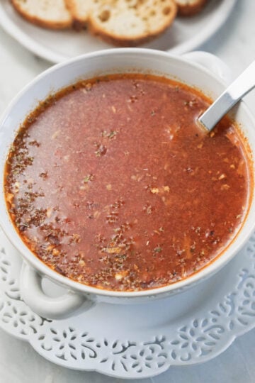 Indian tomato soup in a bowl on a white lace plate.