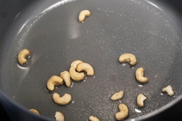 Oil with cashews frying in a pot.