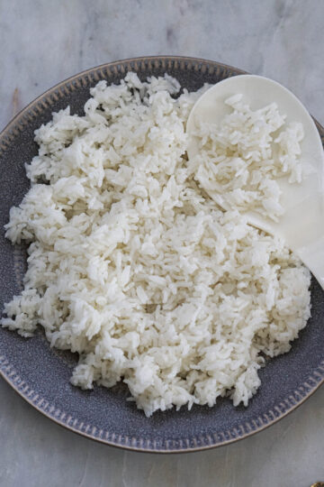 Plate of sona masuri rice with a serving spoon.