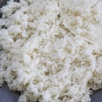 Sona masoori rice on a gray plate with a white serving spoon.