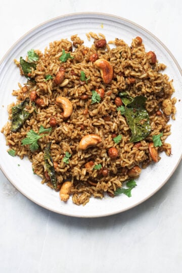 Plate of tamarind rice garnished with cilantro leaves.