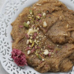 Rajgira sheera in a white lace plate with rose petals and crushed nuts.