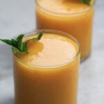 Two glasses of mango juice with mint garnish.