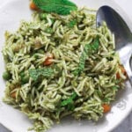Mint rice in a white plate with a silver spoon.