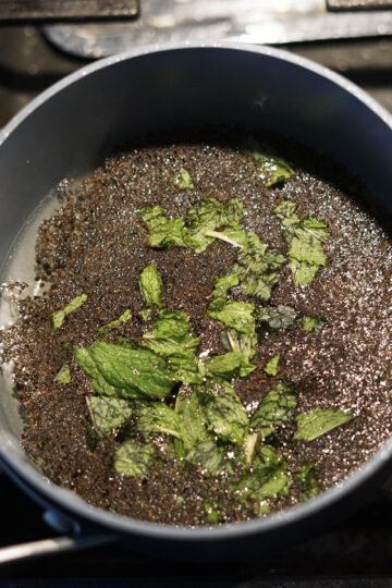 Mint boiling with black tea in water.