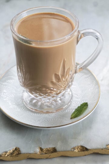 Glass of mint tea with a mint leaf on the side.