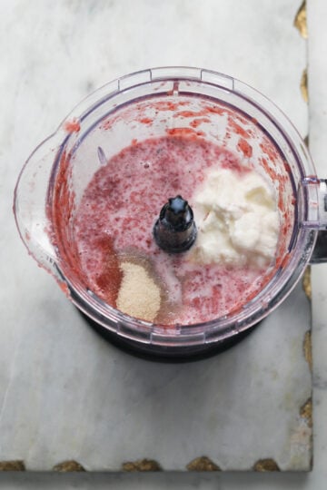 Strawberry lassi ingredients in a blender jar.