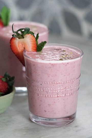 Strawberry lassi in a glass with a strawberry slice garnish.