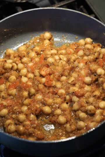 Chickpeas, tomatoes, onions, and spices in pot.