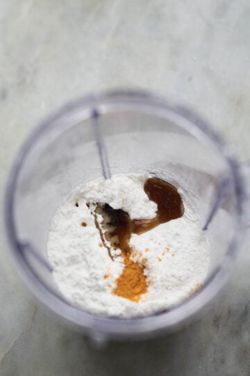 Cornstarch, vanilla extract, and food color powder in a blender jar.