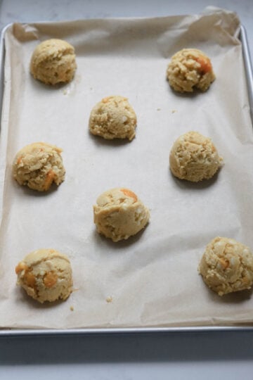 Cookie dough scoops on a parchment paper lined cookie sheet.