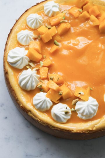 Eggless mango cheesecake with fresh whipped cream, mangoes and mango puree topping.