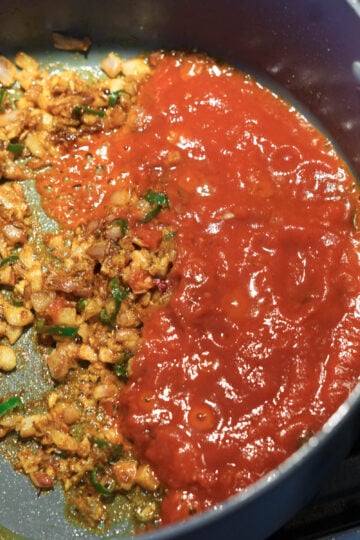 Crushed tomatoes added to aloo gobi matar.