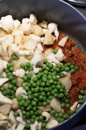 Potatoes, cauliflower, and peas added to pot.