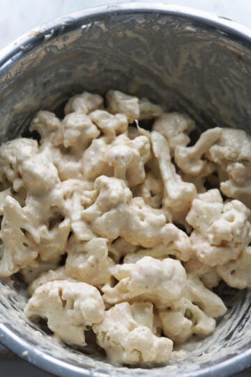 Battered cauliflower florets in a bowl.