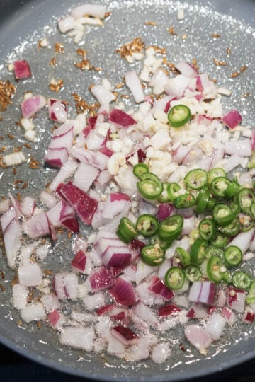 Onions, garlic, and green chili in oil in a pan.