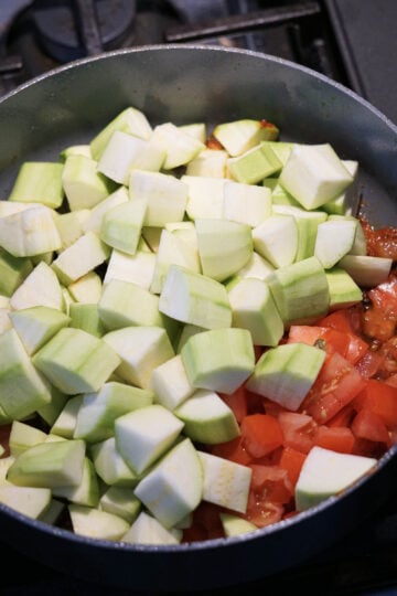 Chopped green zucchini and tomatoes in a pan.