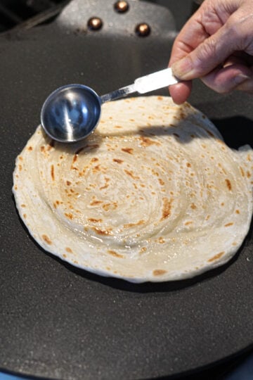 Applying ghee to parotta.