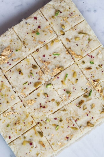 Milk barfi with pistachios, rose petals, and gold foil.
