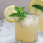 Nimbu pani in a glass with mint leaves garnish.