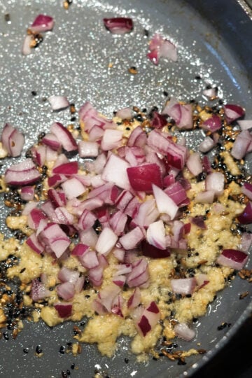 Ginger garlic paste and red onions added to pan.