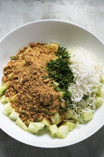 Cucumbers, roasted peanut powder, coconut, and cilantro in a bowl.