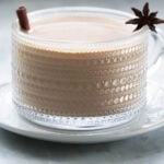 Pumpkin chai latte in a mug with a cinnamon stick and star anise garnish.