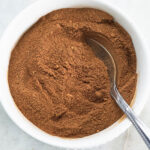 Pumpkin pie spice in a bowl with a spoon.