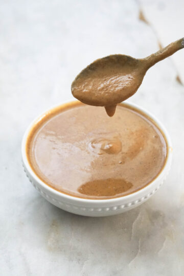 Pumpkin spice sauce dripping off a spoon into a bowl.