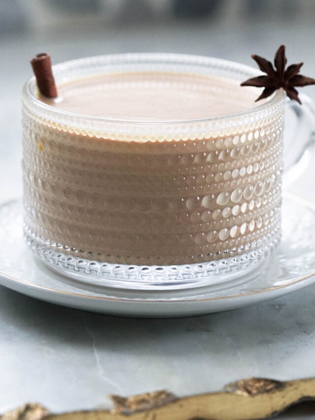 Pumpkin chai latte in a mug with a cinnamon stick and star anise garnish.