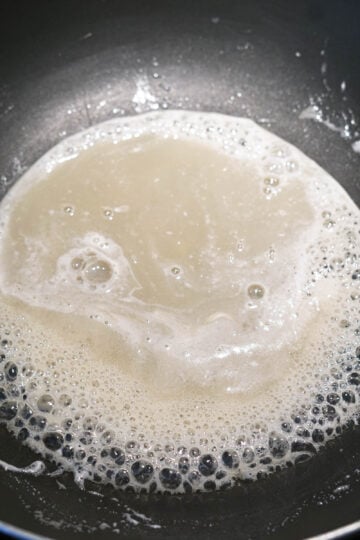 Sugar and milk boiling in a pot.