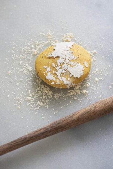 Besan dough ball with besan flour sprinkled on top.