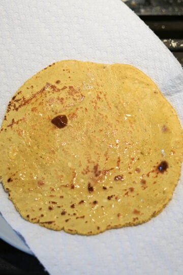 Ghee greased roti on a paper towel lined plate.